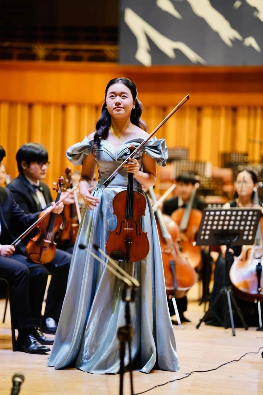Ruby Ngọc Minh on stage with viola after her soloist performance