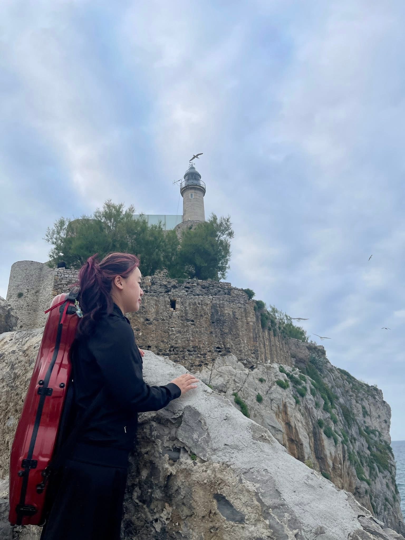 Ruby Ngọc Minh looking toward a Spanish landscape with her viola